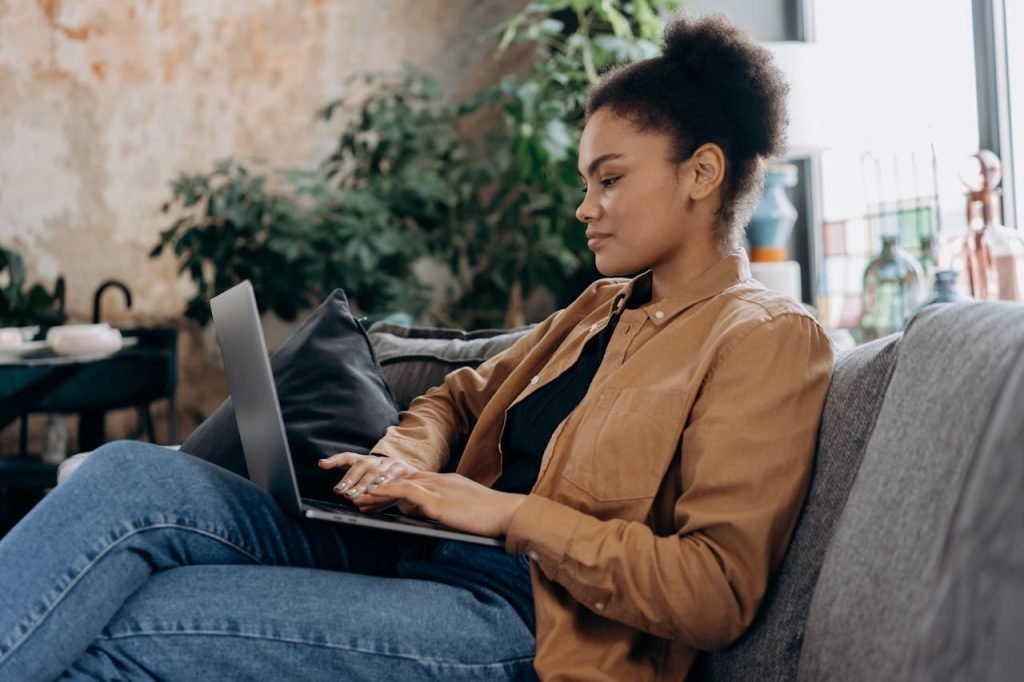 man-person-woman-hand-6893950 A young woman in casual clothing works on her laptop in a cozy home office setting.